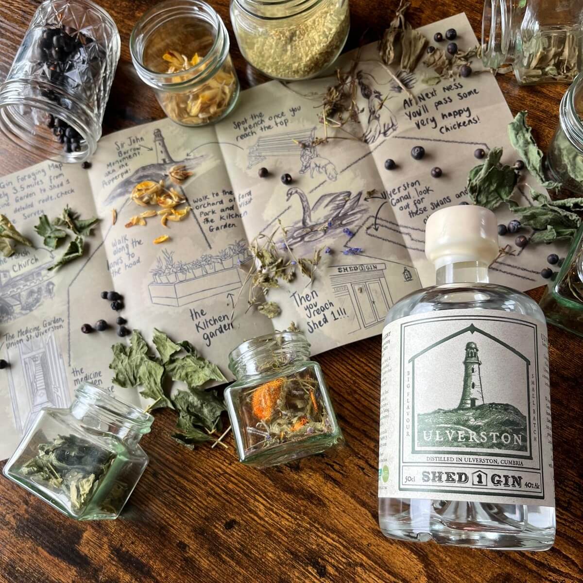 Ulverston Gin Bottle on a table with the foraging map and botanicals all around